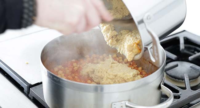 adding pureed chickpeas to a pot