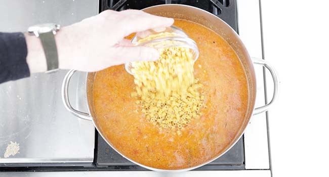 adding pasta to a pot