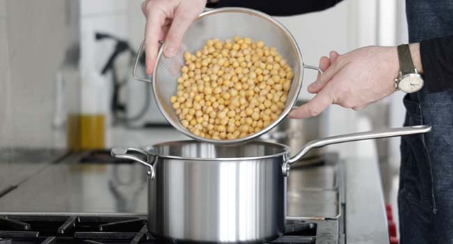 adding chickpeas to a pot