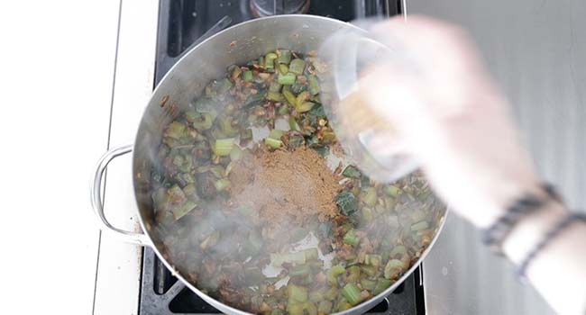 adding spices to peppers and onions