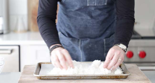 adding coconut shreds to a sheet tray