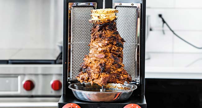 al pastor cooking on a vertical spit