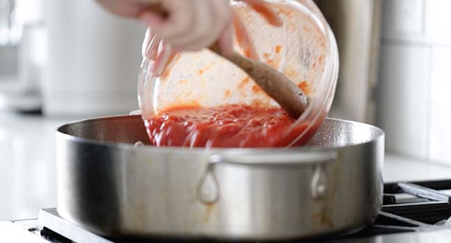 pouring tomatoes into a pot