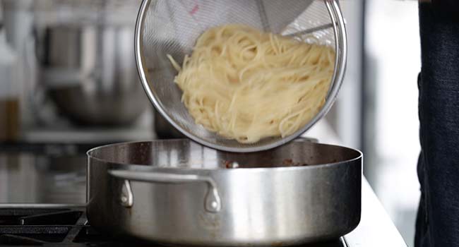 adding pasta to a pan