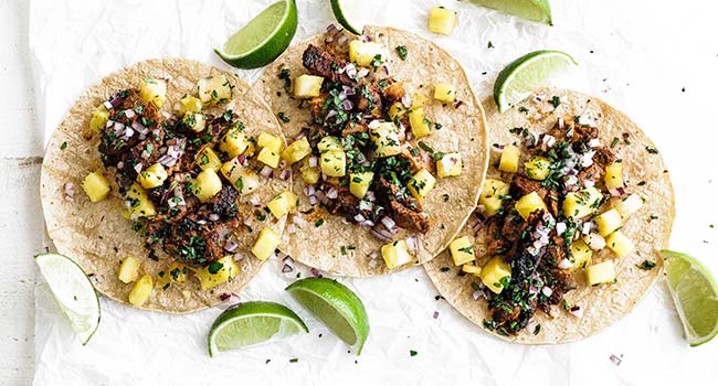 tacos al pastor on tortillas with limes