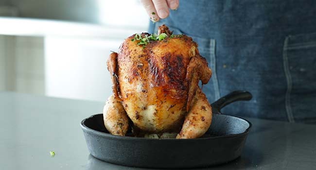 adding green onions to a beer can chicken