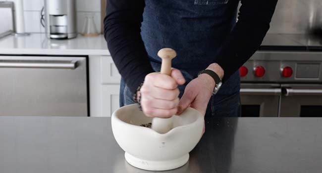 grinding a steak seasoning in a mortar and pestle