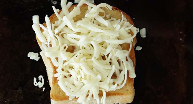 adding shredded cheese to toast