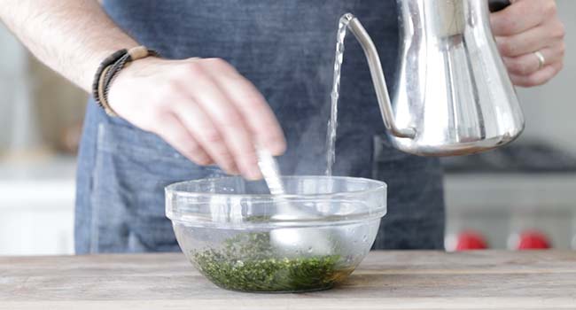 pouring hot water into a bowl with mint