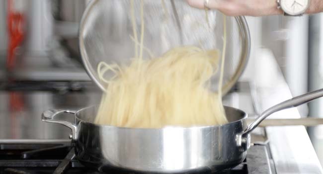 adding pasta to a pot