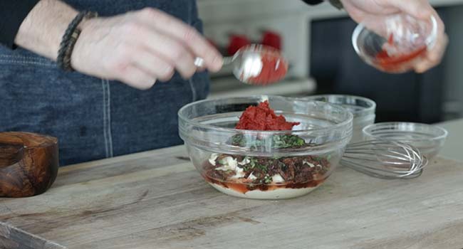 adding tomato paste to a bowl