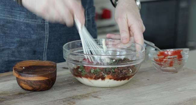 whisking together sun dried tomato mayo