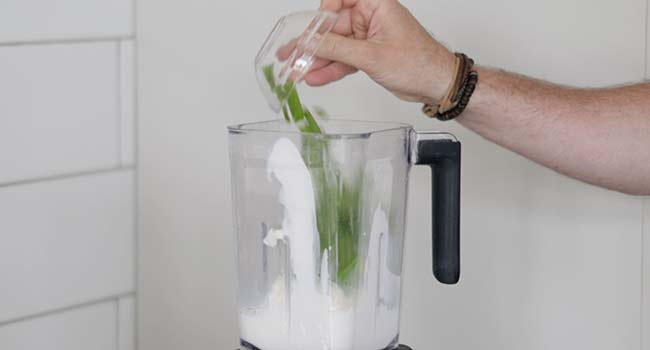 adding cilantro to a blender