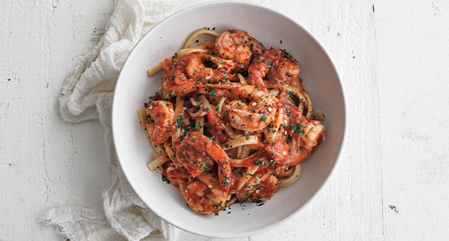 shrimp diavolo in a bowl with pasta and herbs