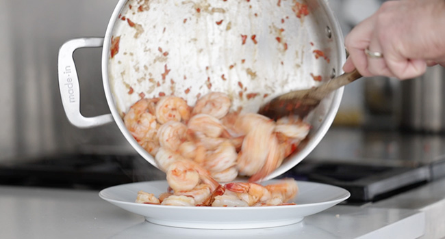 adding cooked shrimp to a plate
