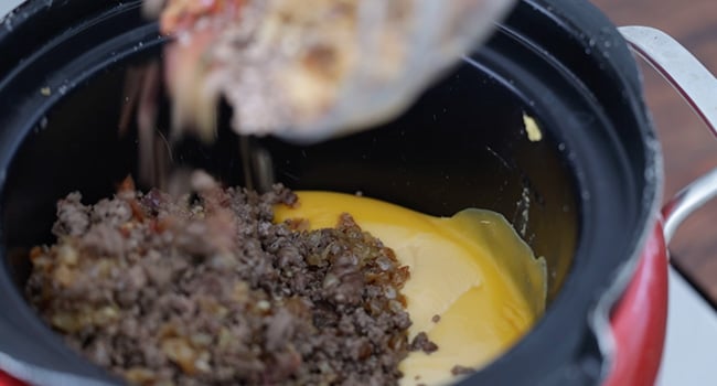 adding cooked beef to a slow cooker