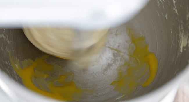 adding egg yolks to a bowl of dough