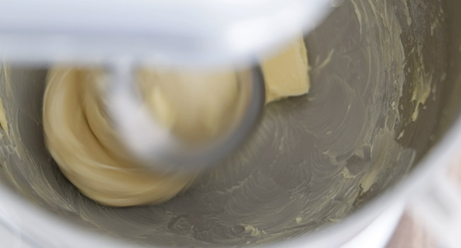 adding butter to a bowl of dough