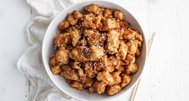 orange chicken in a bowl with sesame seeds