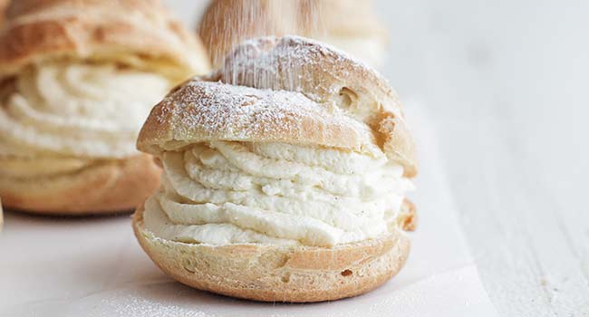 adding powdered sugar to cream puffs