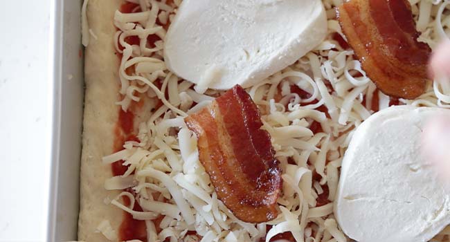 adding bacon and cheese to pizza