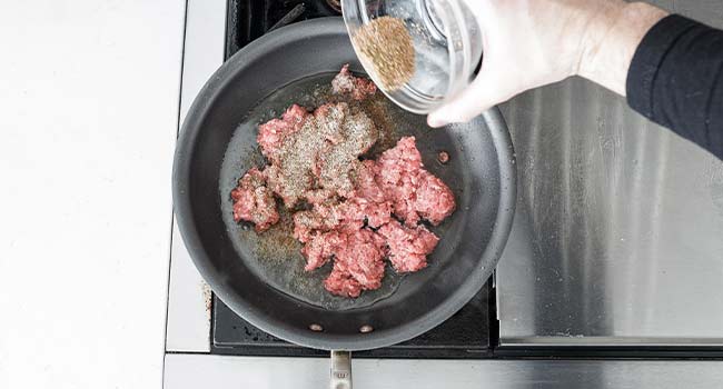 cooking beef in a pan with seasoning