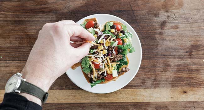 adding cheese to a taco bowl