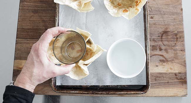 adding a fried tortilla shell to a bowl