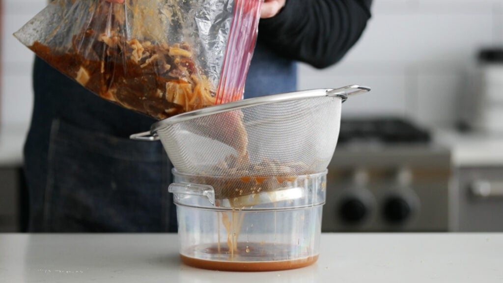 draining the marinade off of a beef bulgogi