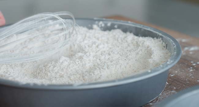 whisking seasoned flour