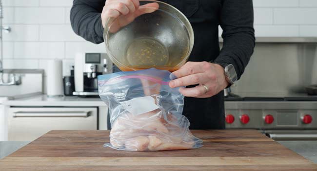 adding an asian marinade to a bag with chicken