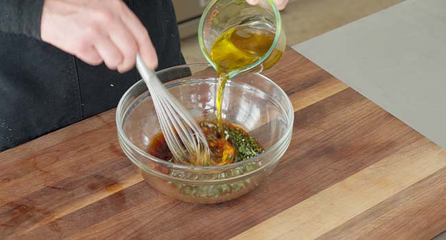 whisking oil into a balsamic chicken marinade