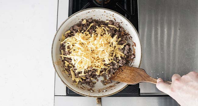 adding cheese to cooked ground beef and onions