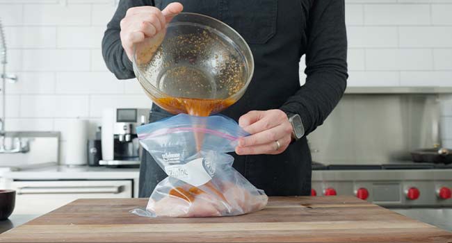 adding chicken fajita marinade to a bag of chicken