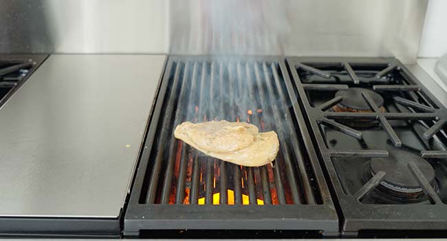 adding a chicken breast to a grill