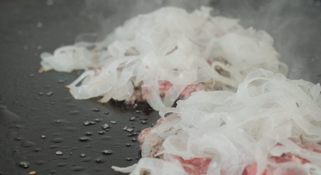 cooking onions on a burger patty