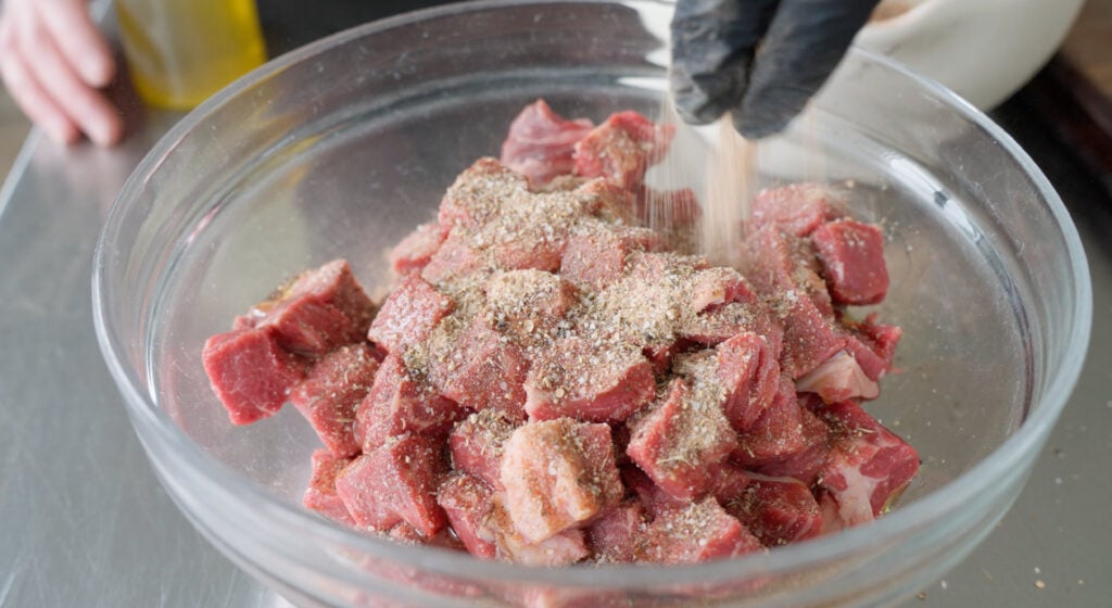 cubed beef in bowl with seasoning