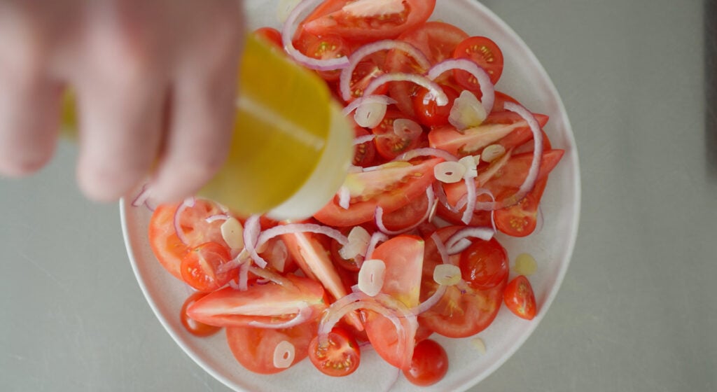 oil beind drizzled on top of italian tomato salad