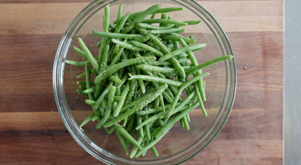 Green Beans tossed with olive oil in bowl