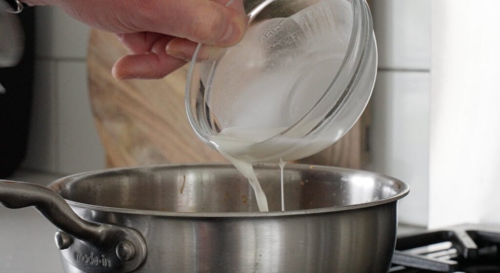 Adding slurry to the pot of sauce