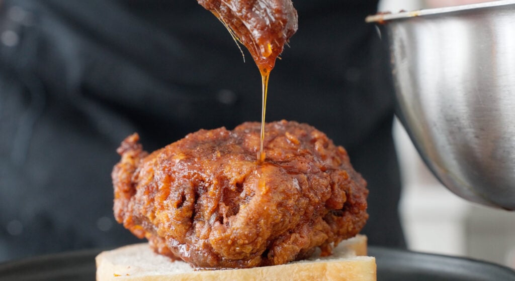 brushing sauce on the fried chicken