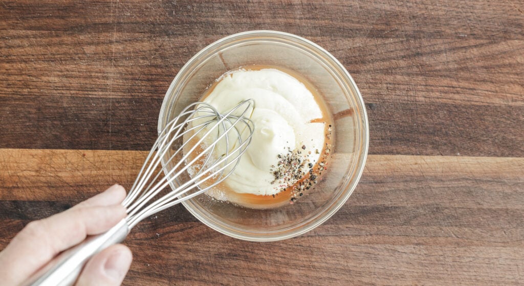 whisking broccoli salad dressing in a bowl
