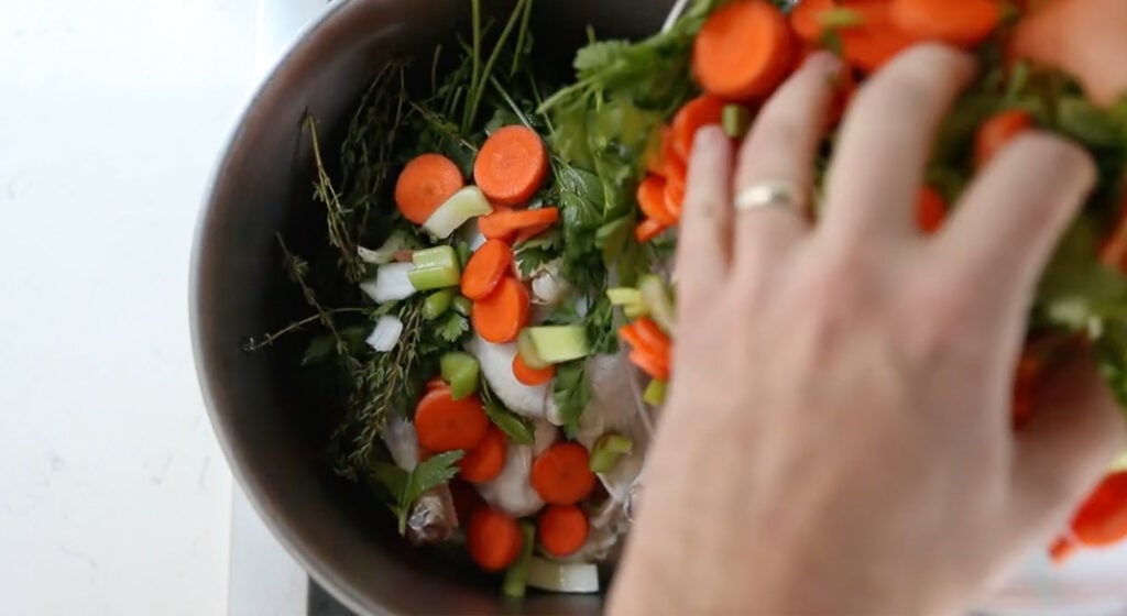 making chicken stock with vegetables carrot, celery and fresh herbs