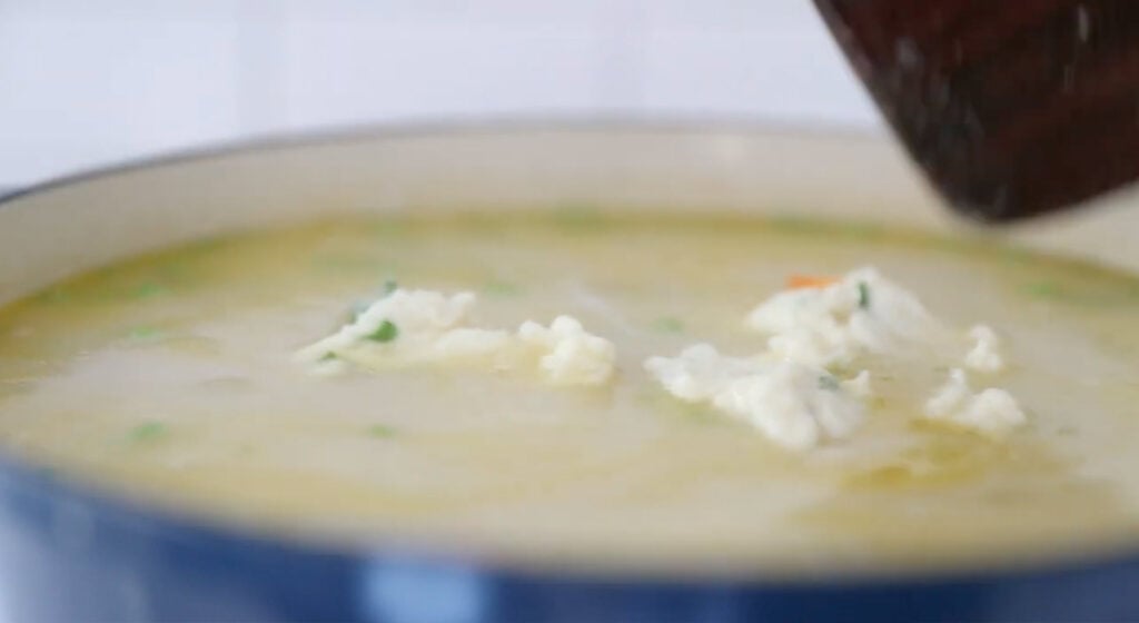 bowl of soup with dumplings, cheese and fresh herbs
