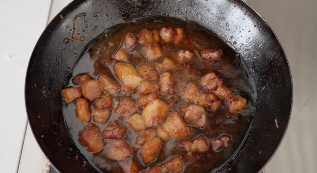 Pork in wok with sauce ingredients.