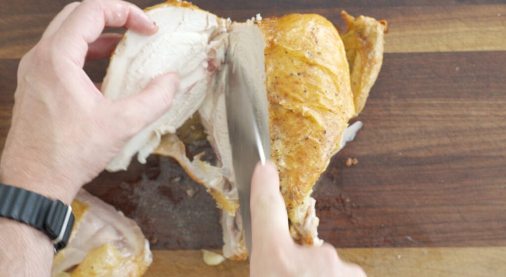 Carving the breast meat from the whole chicken