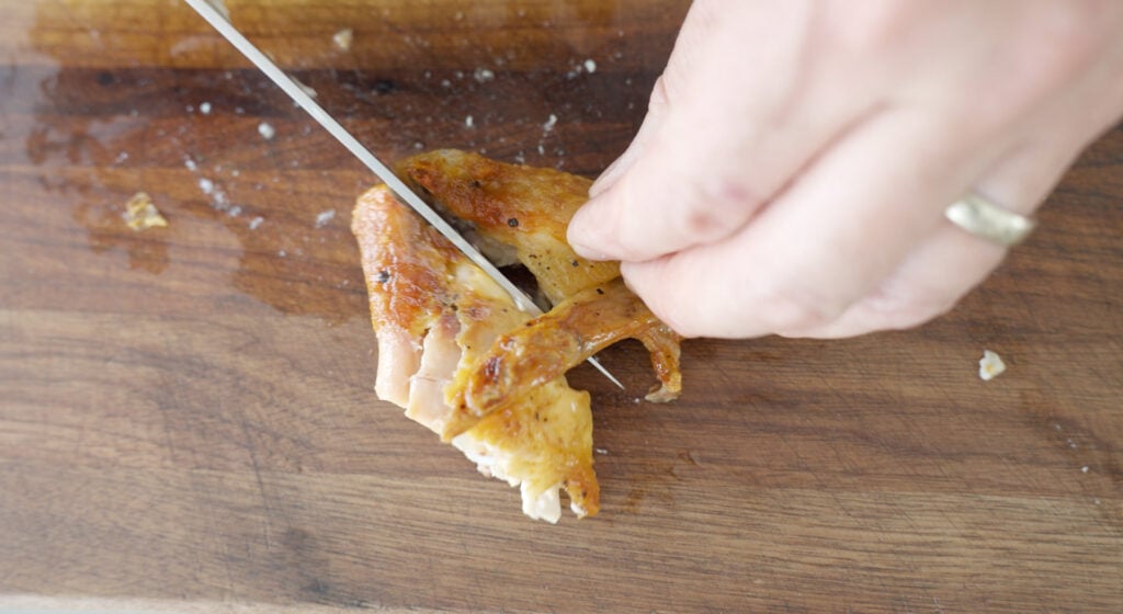 Knife slicing to separate chicken leg and thigh