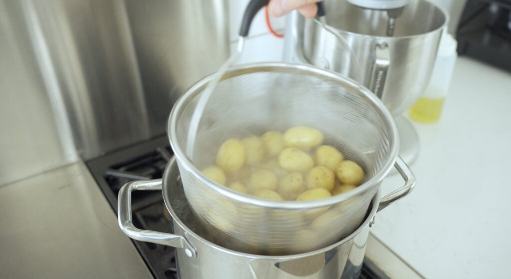 Baby Potatoes in a strainer basked in a pot of bowling water