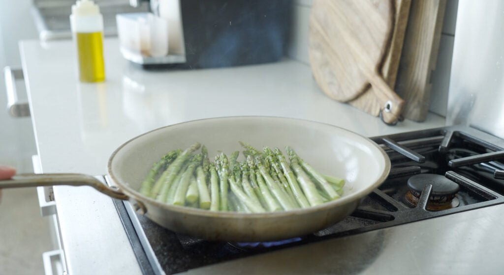 Asparagus lined side by side in a pan on the stove