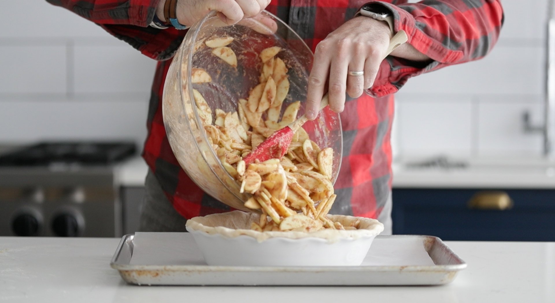 adding apples to pie dough in a pan